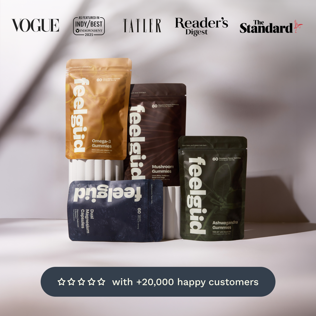 Four stand-up pouches of feelsgid gummies arranged on a white surface against a softly lit gray background. The pouches are tan, dark brown, dark blue, and dark green, each with the feelsgid brand name prominently printed vertically.